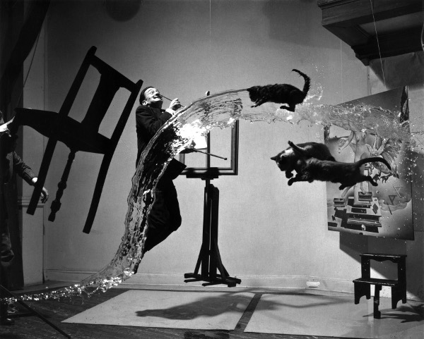 4th House Uranus, 5th House Uranus, 6th House Uranus: black-&-white surrealistic photo of a chair, a man, water flow, a cat and other creatures frozen in the air, all captured by camera. 